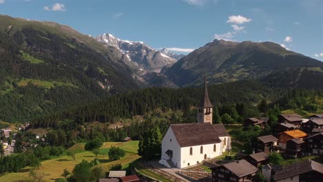 A quaint village in the mountains with a church surrounded by nature, aerial view