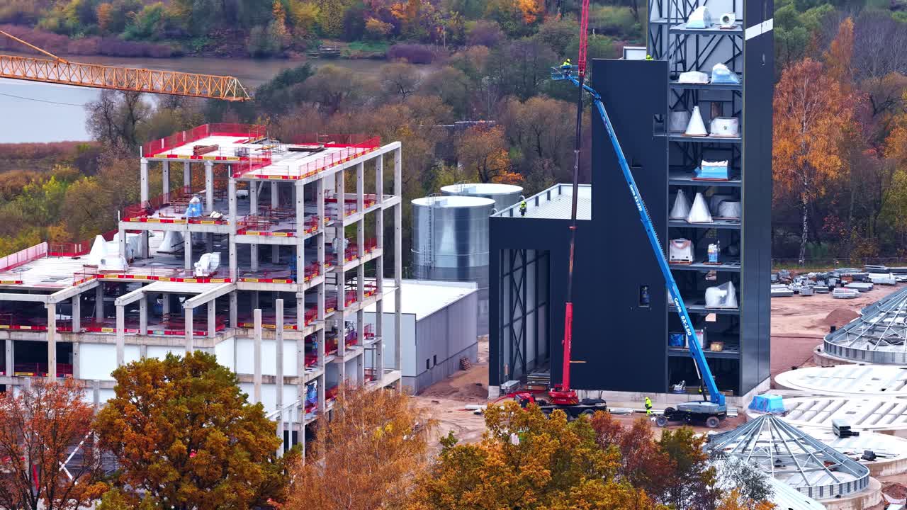 An Industrial Facility is Under Construction Amid Autumn Trees - Aerial Drone Shot