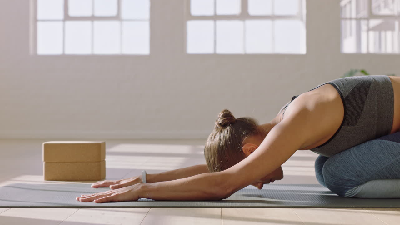 gesunde yoga-frau praktiziert die pose ihres kindes und genießt den fitness-lebensstil, indem sie im studio trainiert und schönes körpertraining auf der trainingsmatte bei sonnenaufgang ausdehnt