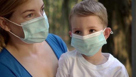 madre abraza a su hijo con máscaras médicas mientras está sentada en un parque 04