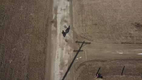 Aerial-drone-shot-of-a-young-high-school-aged-teen-boy-wearing-a-backpack-walking-down-the-road-to-school