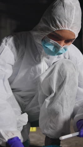 a crime scene investigator in a white hazmat suit collects evidence from a crime scene