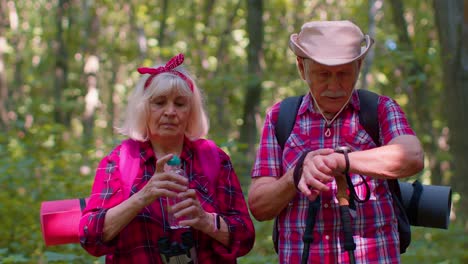 cansados sedientos excursionistas mayores abuela abuelo entrenamiento nórdico caminando agua potable en el bosque