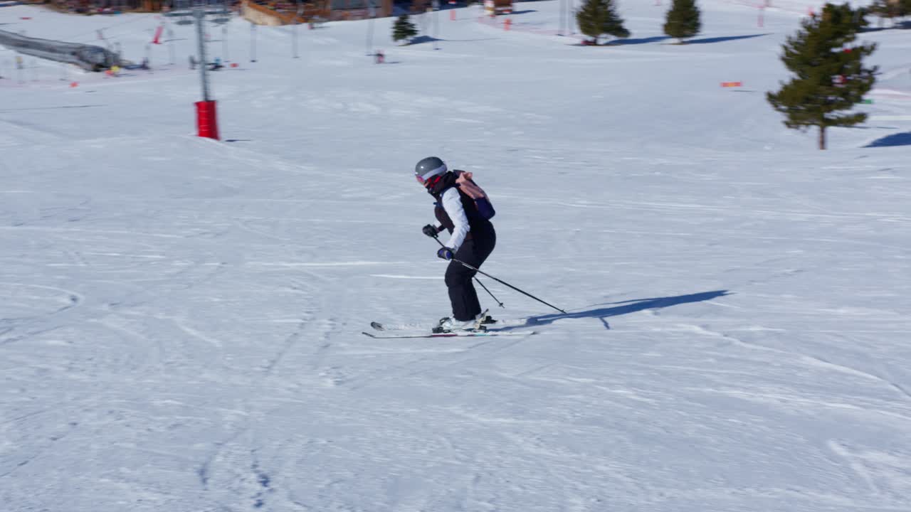 화창한 날 눈 덮인 슬로프에서 슬로우 모션으로 스키를 타는 여성