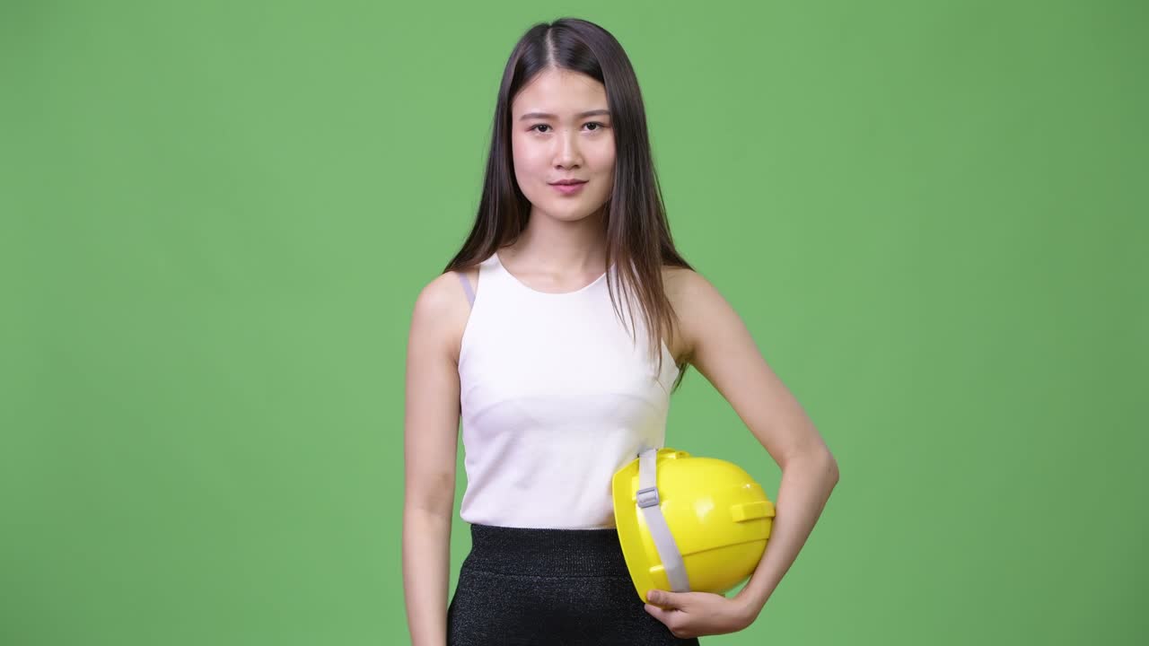 Young beautiful Asian businesswoman as engineer pointing up