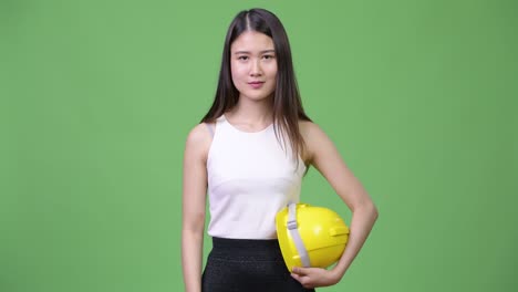 young beautiful asian businesswoman as engineer pointing up