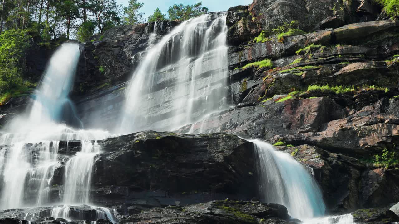 Een adembenemend uitzicht op een waterval die over een steile klif stort, het water glinstert terwijl het sierlijk stroomt te midden van het weelderige landschap