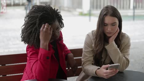 mujeres afroamericanas y caucásicas deslizando fotos en el teléfono