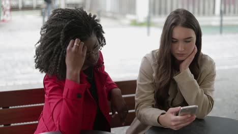 afro-american and caucasian women swiping photos on phone