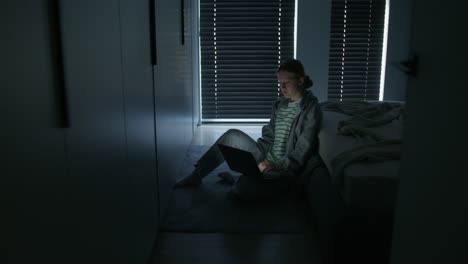 teenage girl working on laptop in her bedroom at night