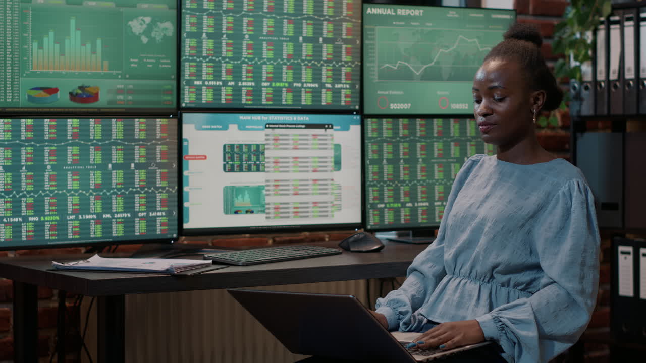 Female investor looking at real time stocks on laptop and multiple monitors