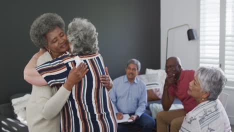 diverse group of senior friends giving support to african american female friend on meeting