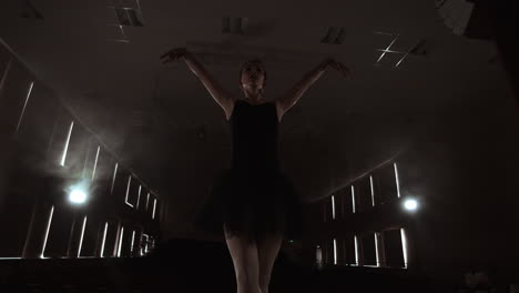 slow motion: prima ballet in a black dress performs rotations and dance graceful movements rehearsing a solo program. the camera moves on gimbal.