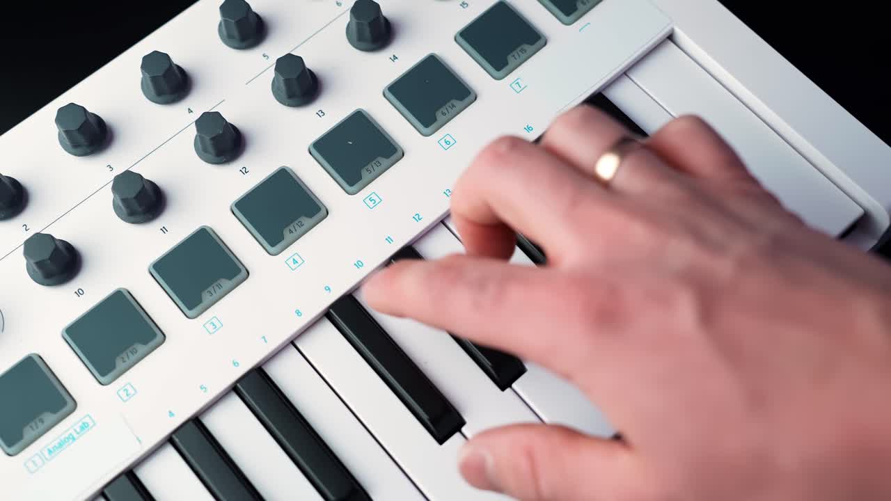 Primo piano di una mano che gira una manopola su un controller tastiera MIDI compatto con pad, mostrando un vero flusso di lavoro da home studio per modellare il suono durante la produzione musicale.
