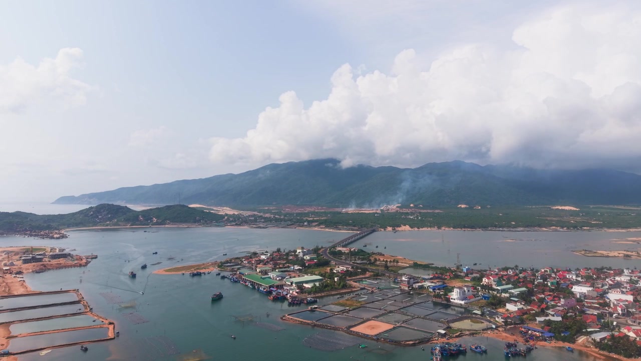 Biển Lỗ Quang ở Việt Nam mang đến cái nhìn về những tòa nhà ven sông, núi ở hậu cảnh và thuyền trên biển. Những đám mây phủ kín bầu trời và tô điểm thêm cho khung cảnh khu vực.