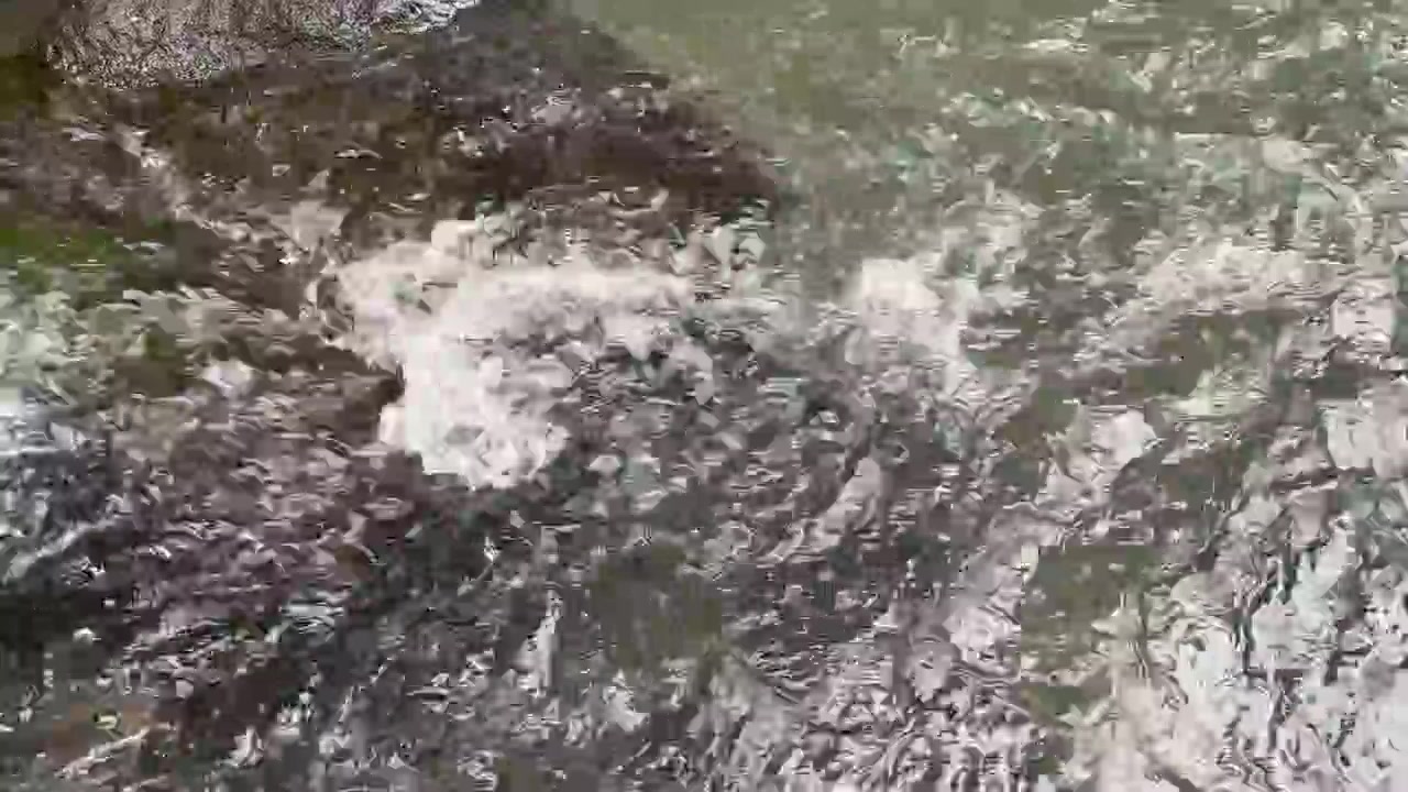Agua cristalina fluyendo y salpicando sobre rocas oscuras