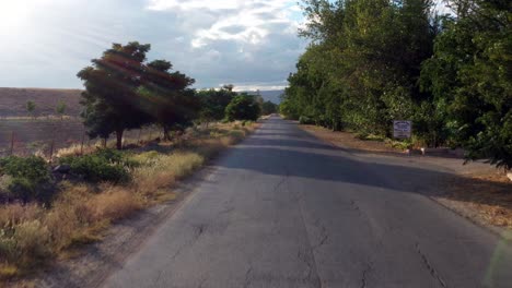 a tilt up shot of an empty intercity road between green agricultural fields