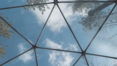 a timelapse of a view from the inside of a geodesic dome accommodation airbnb during a beautiful spring sunny day located in the middle of the forest shot in 4k