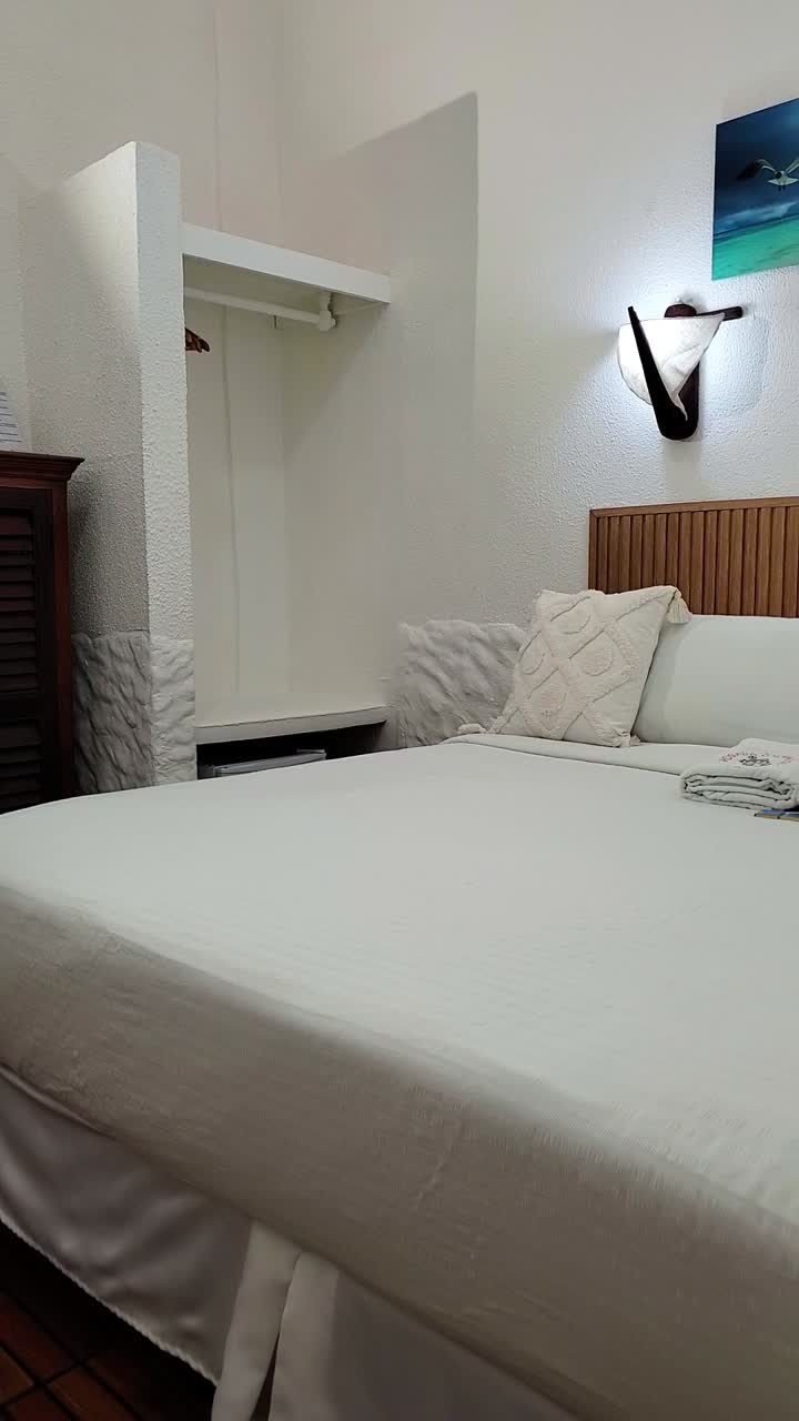 Vertical shot modern, clean bedroom with white linens and a minimalist design