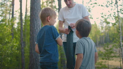 father and two sons 3-5 years together on a hike set up a tent