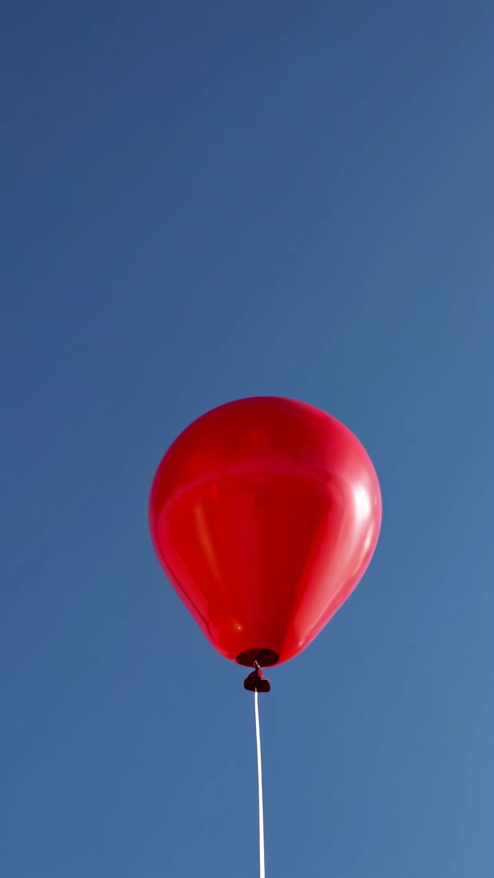 Palloncino rosso vibrante che galleggia contro un cielo azzurro brillante