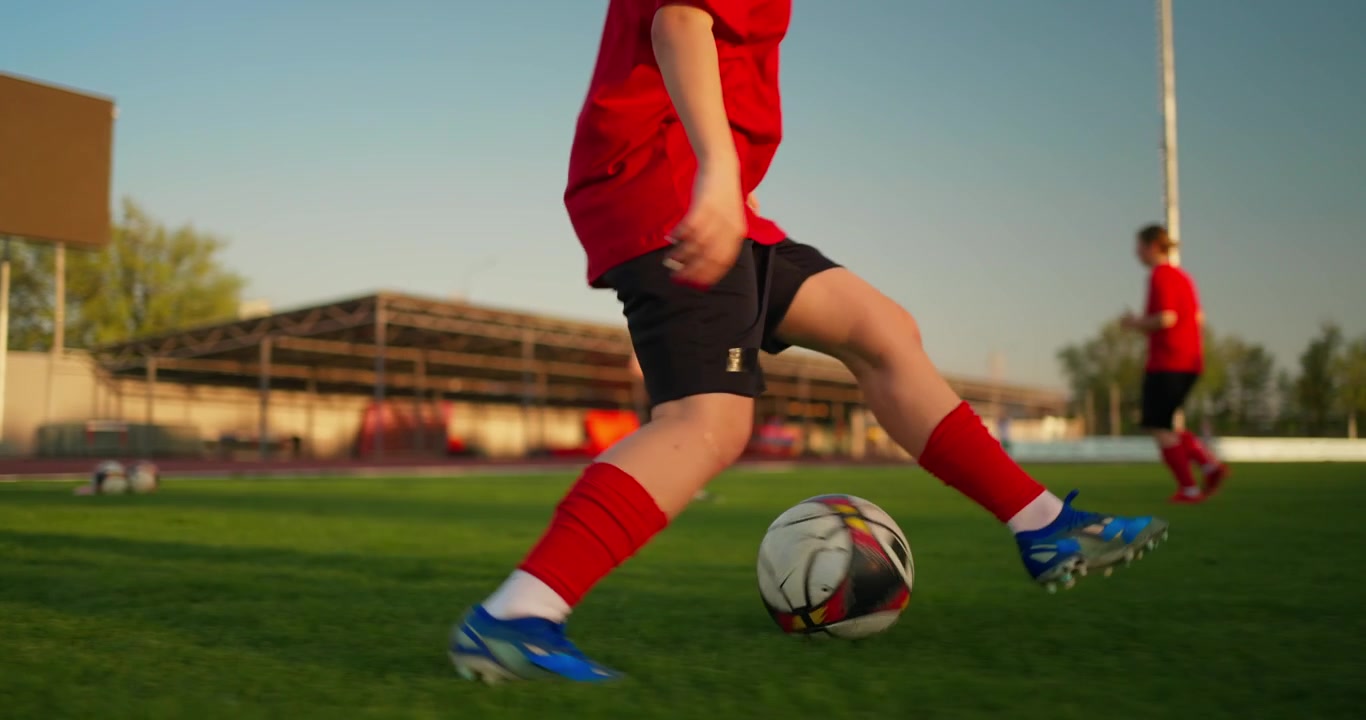 Calciatrice che dribbla il pallone su un campo verde durante l'allenamento