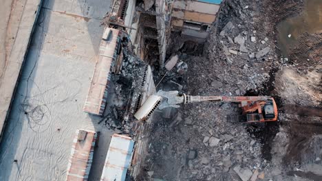 bulldozer with mechanical arm. falling concrete slab. excavator demolishing ruins for new construction project. flying above a destruction