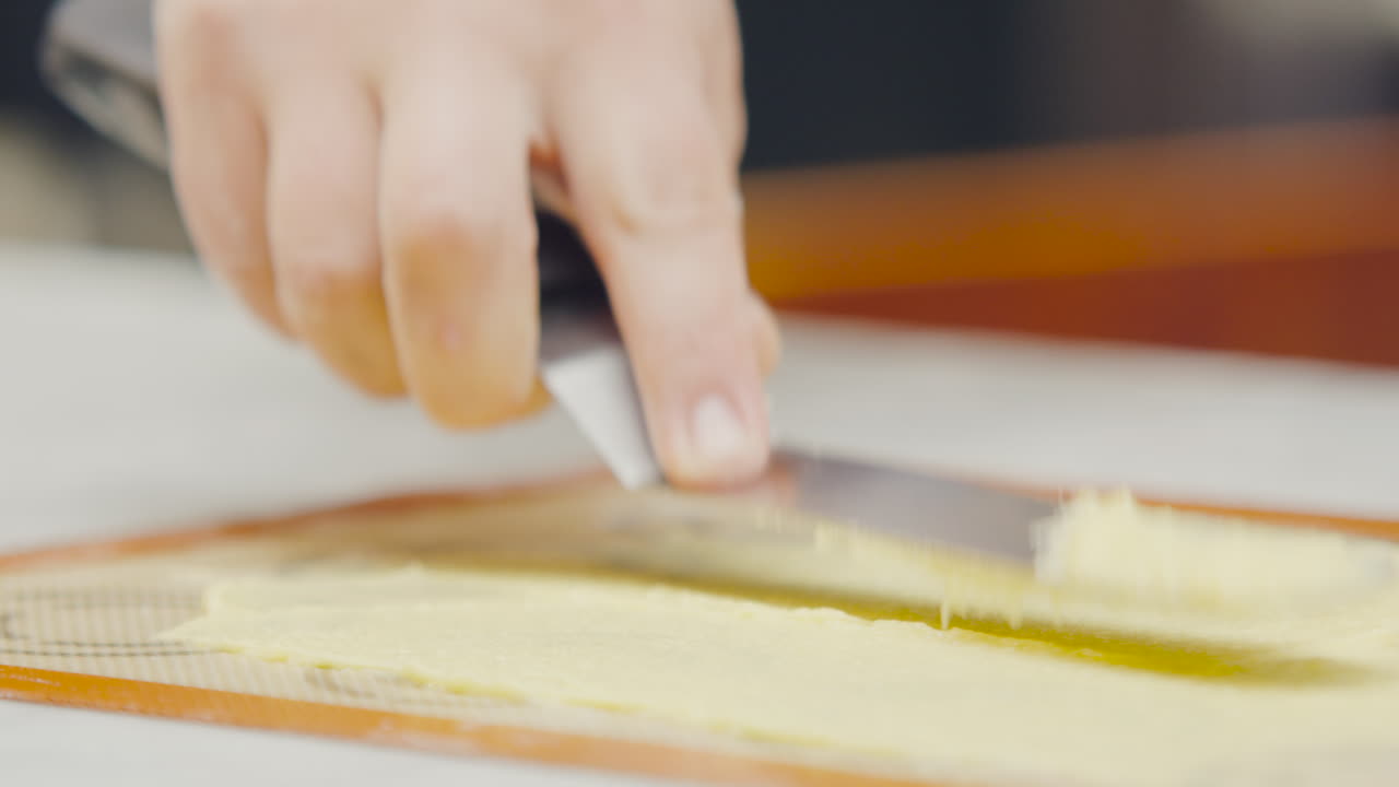 Hand spreading dough with a spatula on a baking mat