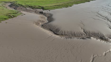 muddy riverbank overhead birds eye drone aerial view green grassy riverside