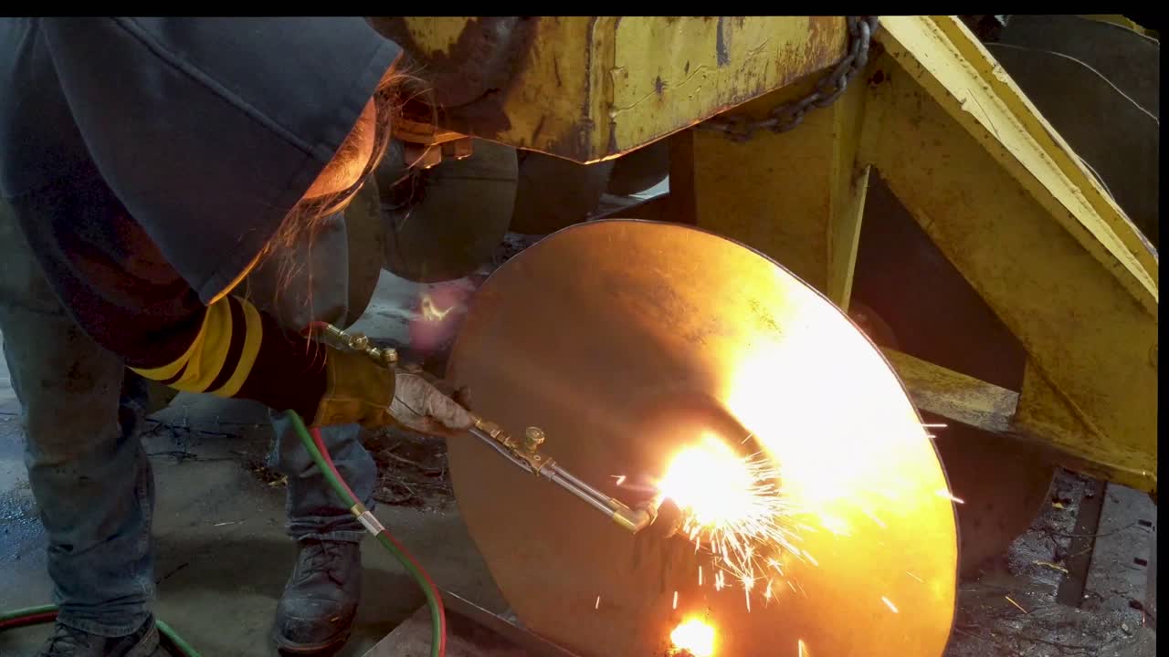 A man cut's a large piece of steel with a cutting torch