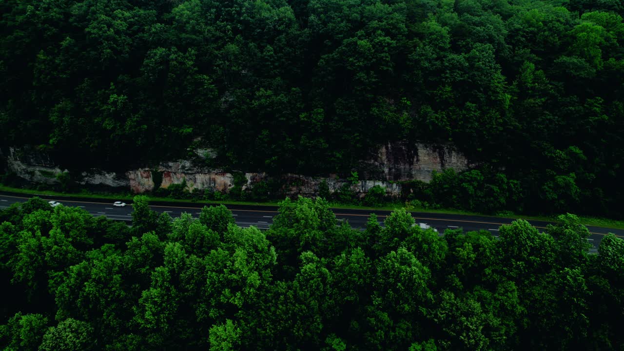 Flatbed Semi Truck Hauling Cargo Along a Scenic Forest Rock Cut Highway. Tennessee