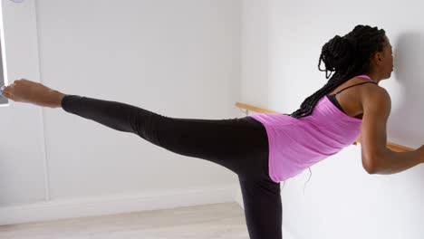 mujer estirando su pierna en la barra en el estudio de fitness 4k