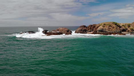 Aerial-drone-view-towards-waves-hitting-the-Headland-bay,-at-the-Emerald-Beach