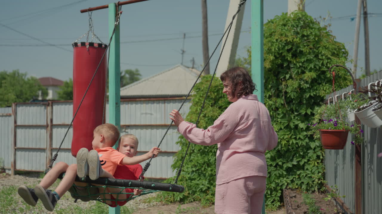 Nonna e nipoti giocano felici all'aperto, l'anziana osserva i bambini gioiosi durante le attività all'aperto, i membri della famiglia si godono insieme attività ricreative all'aperto.