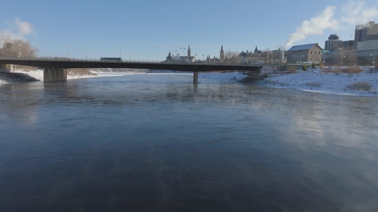 Drone che vola basso sul fiume Ottawa avvolto nella nebbia, verso il ponte Portage con lo skyline di Parliament Hill sullo sfondo
