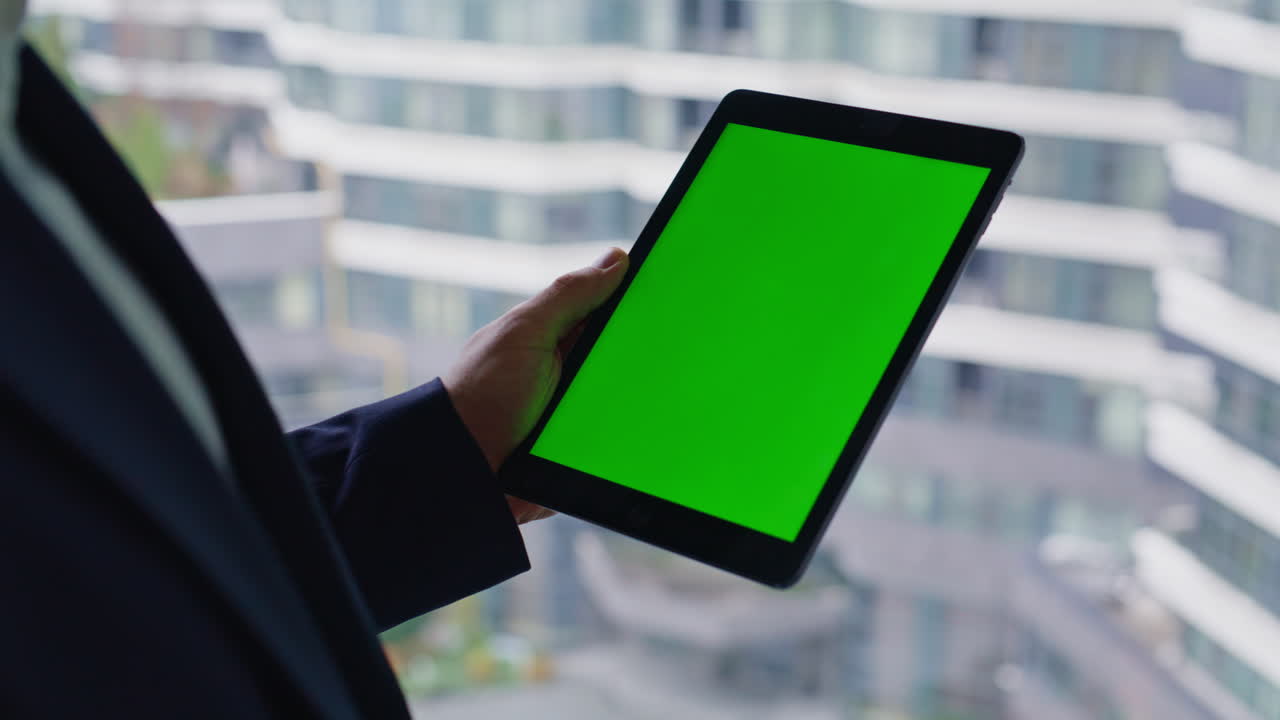 사무실 에서 녹색 스크린 을 가진 태블릿 을 들고 있는 사람