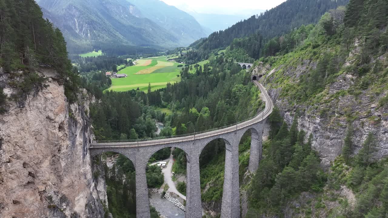 Aerial view of the Landwasser Viaduct in Switzerland, showcasing its remarkable six-arched limestone railway bridge. This iconic, curved structure exemplifies outstanding engineering.