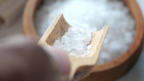 close up of white salt crystals in a wooden scoop