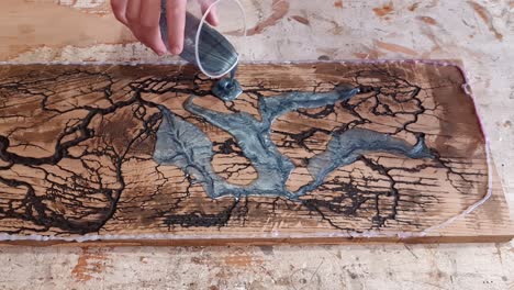 Pouring-Epoxy-Resin-on-burned-wood-with-holes-to-make-cutting-board