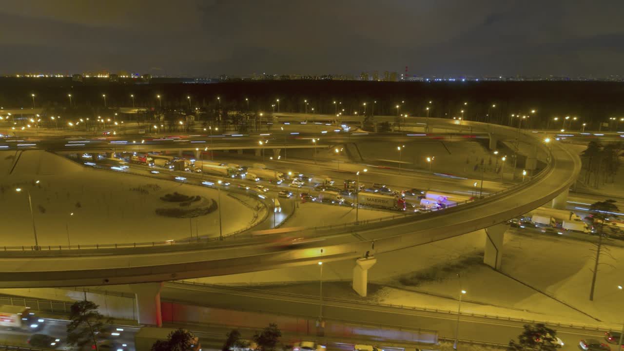 """겨울 저녁에 복잡한 조명 고속도로 교차로, 공중 하이퍼스, 드론이 뒤로 날고 위로 날고, 공개 을 설정합니다."""