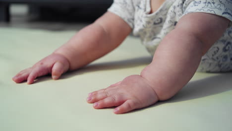 tilting shot from baby's hands to his face while he attempts to learn how to crawl