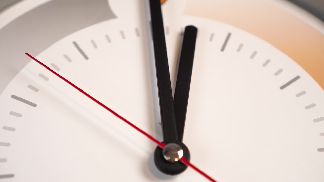 오렌지색과 회색 패턴이 있는 색 다이얼에 빨간색 세컨드 손과 검은색 분과 시간 손으로 시간을 지나갑니다.