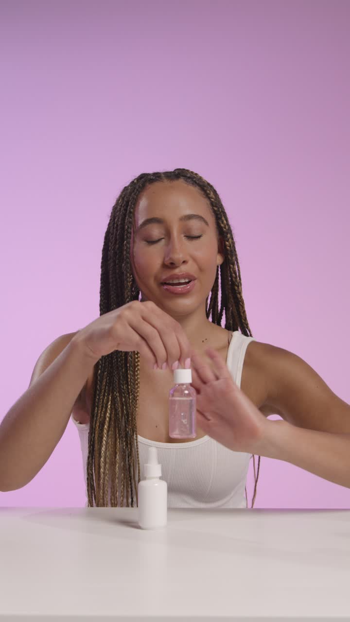 joven grabando belleza maquillaje revisión o tutorial para el cuidado de la piel suero a la cámara para los medios sociales canal 5