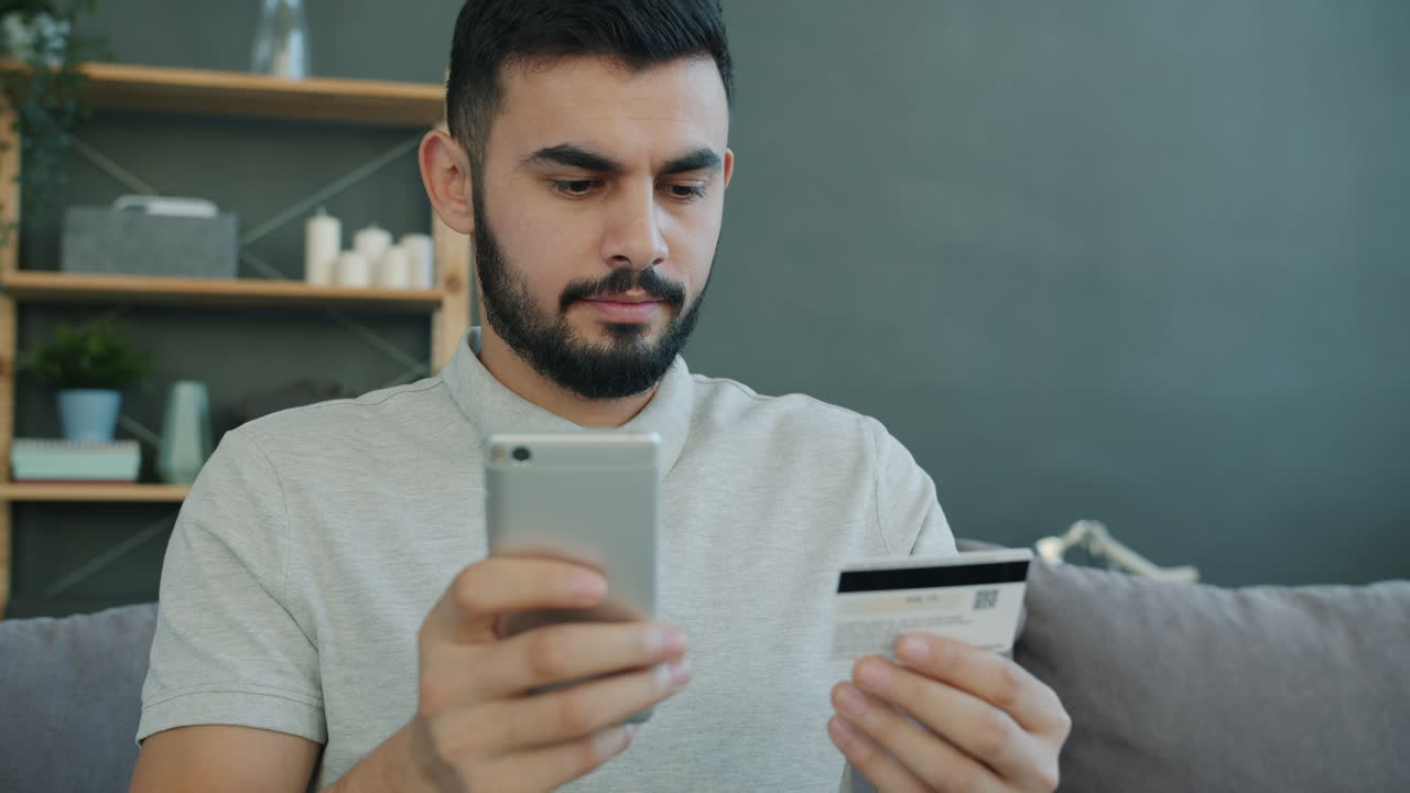 Man using mobile phone and credit card for online payment.