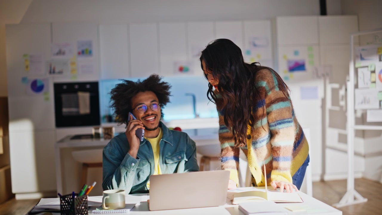 Man talking mobile phone, woman pointing laptop. Multiethnic remote work team.