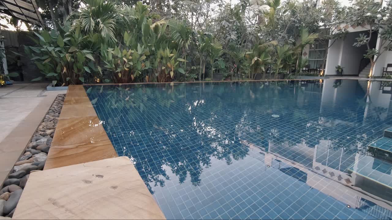 Glideroptagelse af en krystalklar swimmingpool i et tropisk hotels område