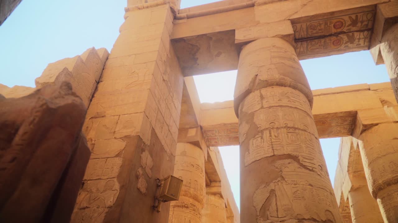 Tall pillars and pylons in the Karnak Temple, Luxor Egypt. Intricate carved drawings and hieroglyphs adorning the pillars. Slow slide movement sideways.