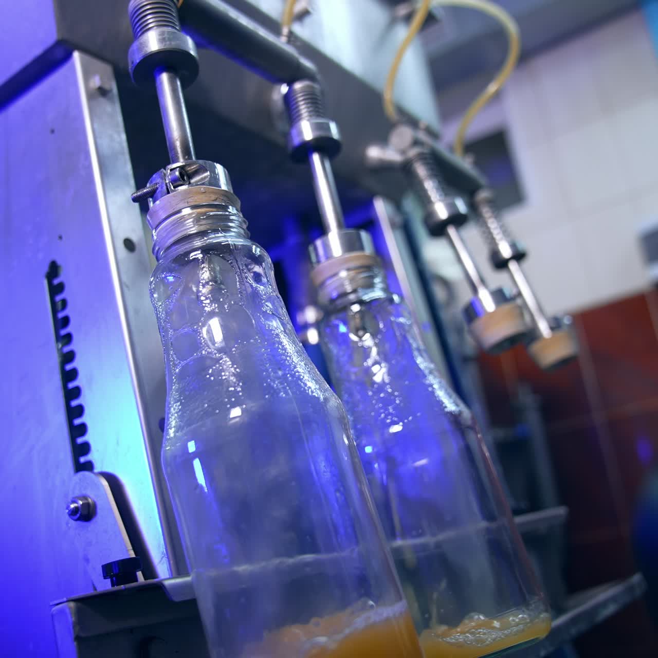 Glass bottles being put under the automatic system of filling. Freshly made apple juice poured into the bottles at modern food factory
