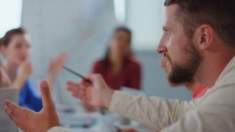 Side-view-aggressive-man-arguing-with-colleagues-in-meeting-room