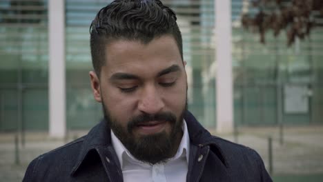 Focused-bearded-man-using-cell-phone-on-street